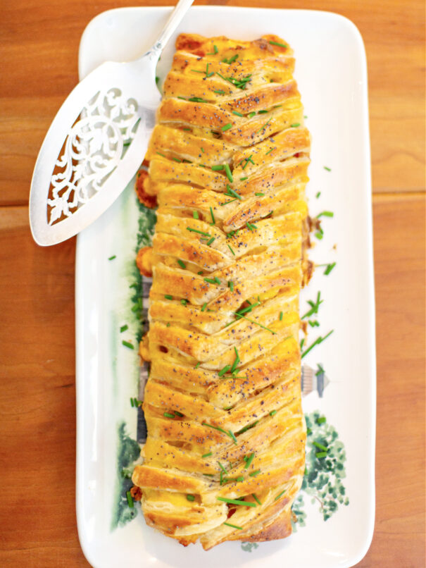 Braided breakfast pastry on a long serving dish, with a silver server.