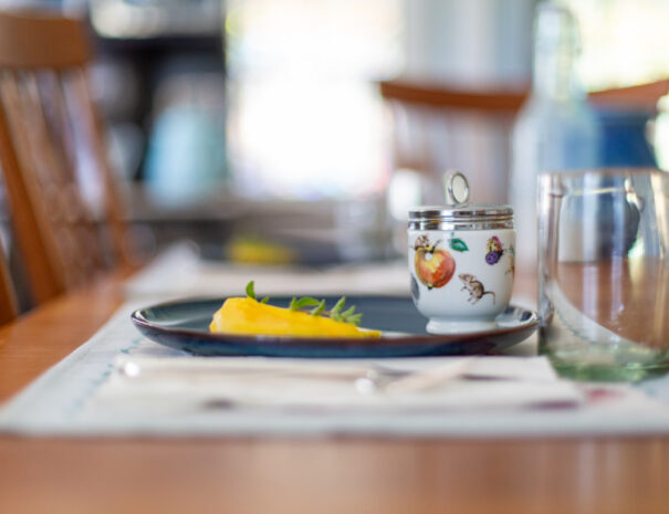 Large egg coddler on a plate with sliced mango.
