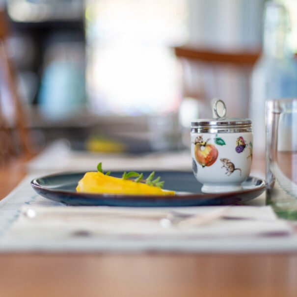 Large egg coddler on a plate with sliced mango.