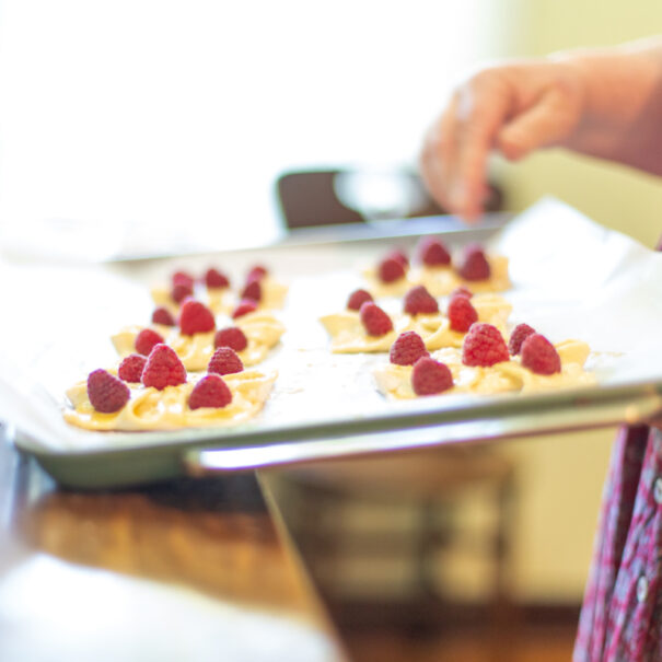 Unbaked raspberry tarts on a baking tray.