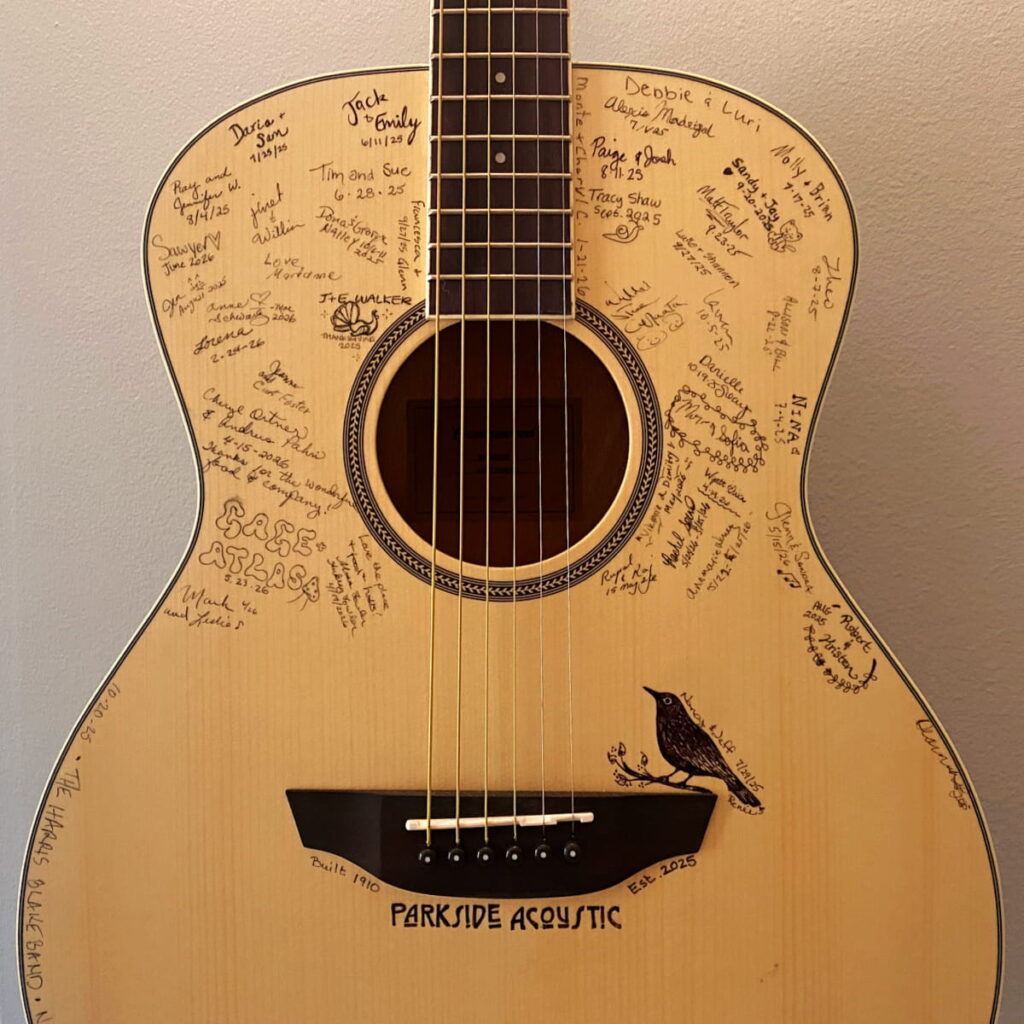 Close-up of the front of a guitar with signatures on it.